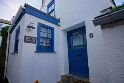a blue door on the side of a white building at Grade II Listed Cottage Gorran Haven Sea Views in Gorran Haven