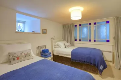 a bedroom with two beds and a window at Grade II Listed Cottage Gorran Haven Sea Views in Gorran Haven