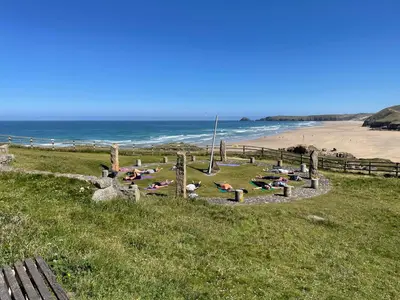 a group of people laying on the grass near a beach at Seaside Cabin Perranporth in Perranporth
