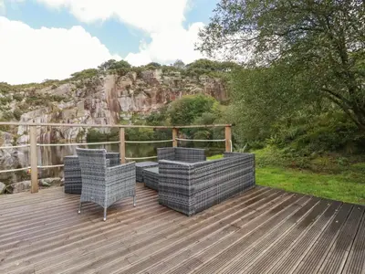 a deck with chairs and a view of a mountain at Tickeydoo, Tor Down Quarry in Bodmin