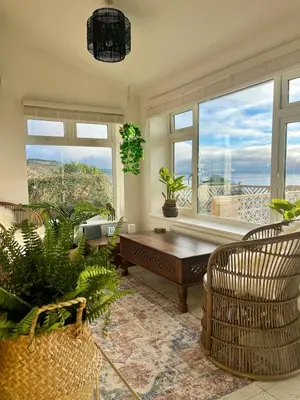 a living room with a table and a large window at Luxury Cornish Seaview Bungalow in Looe