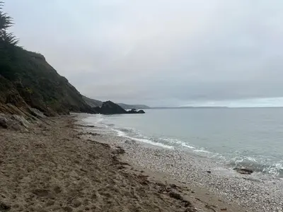 a beach with a rocky shoreline next to the ocean at Luxury Cornish Seaview Bungalow in Looe