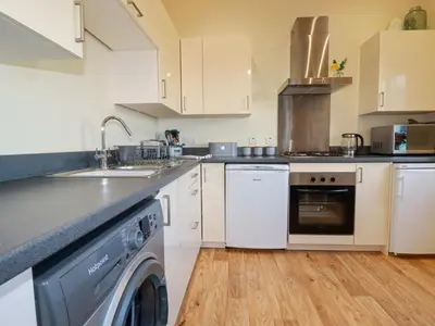 a kitchen with white cabinets and a dishwasher at Freesia in Truro