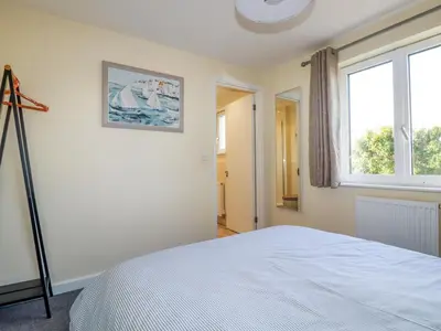 a white bedroom with a bed and a window at Freesia in Truro