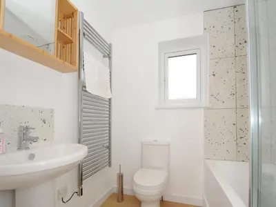 a white bathroom with a toilet and a sink at Sea Spray in Port Isaac
