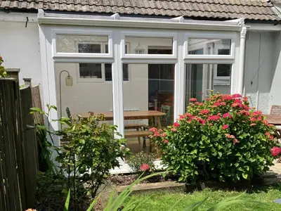 a conservatory with a sliding glass door and flowers at Sea Spray in Port Isaac