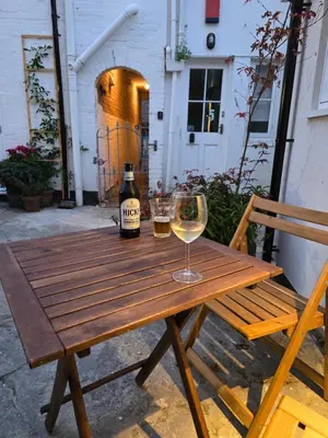 a wooden table with a bottle of wine and a glass at 4 Tre Pol Pen, and the Wash Kitchen in St Ives