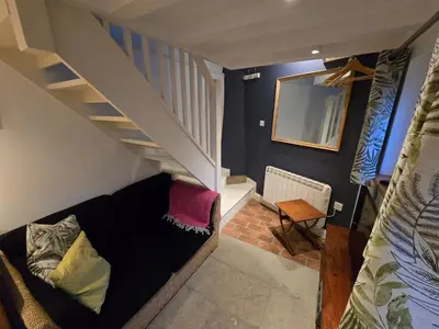 a living room with a black couch under a stairs at 4 Tre Pol Pen, and the Wash Kitchen in St Ives