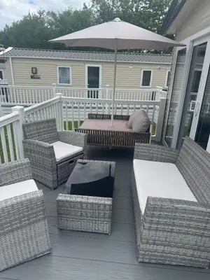 a porch with wicker chairs and an umbrella at Wallows Lodge with private hot tub in St Austell