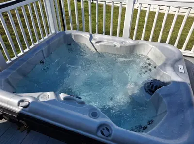 a hot tub on a deck with blue water at Wallows Lodge with private hot tub in St Austell