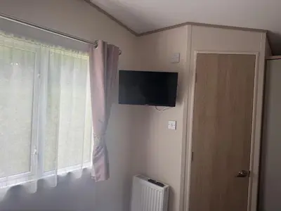 a room with a tv and a window and a door at Wallows Lodge with private hot tub in St Austell