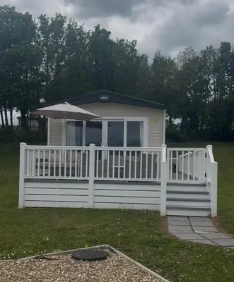 a small house with a white fence and an umbrella at Wallows Lodge with private hot tub in St Austell