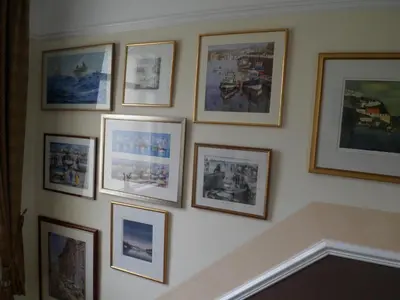 a wall filled with pictures on a wall at Wild Air Guest House in Mevagissey