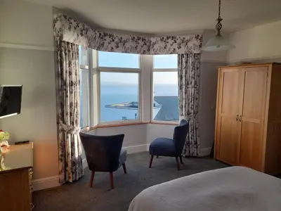 a bedroom with a large window with a view of the ocean at Wild Air Guest House in Mevagissey