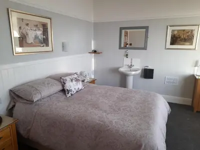 a bedroom with a bed and a sink in it at Wild Air Guest House in Mevagissey