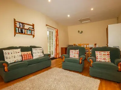 a living room with two green couches and a rug at The Coach House in Camelford