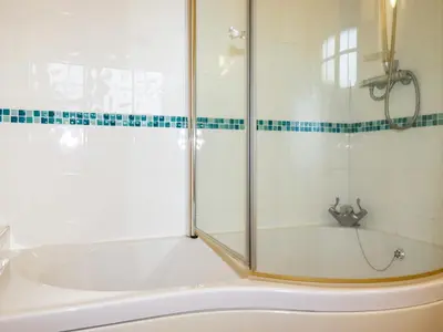 a white bath tub with a glass shower door at The Coach House in Camelford