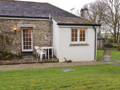a small cottage with a table and chairs in a yard at The Coach House in Camelford
