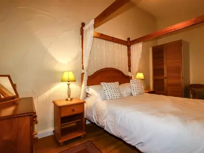 a bedroom with a large bed with a wooden headboard at The Coach House in Camelford
