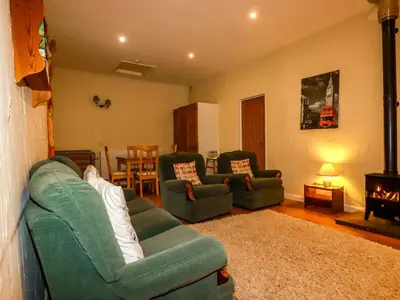 a living room with two green couches and a fireplace at The Coach House in Camelford