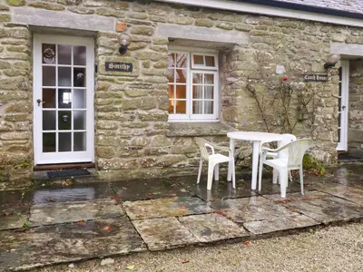 a table and chairs in front of a stone house at The Smithy in Camelford