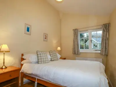 a bedroom with a white bed and a window at The Smithy in Camelford