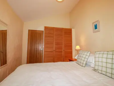 a bedroom with a white bed and a wooden cabinet at The Smithy in Camelford