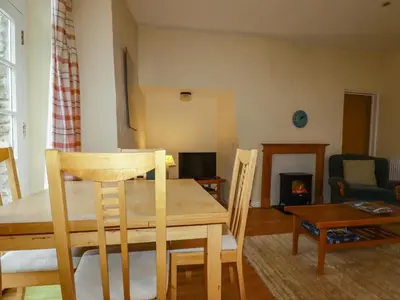 a dining table and chairs in a living room with a fireplace at The Smithy in Camelford
