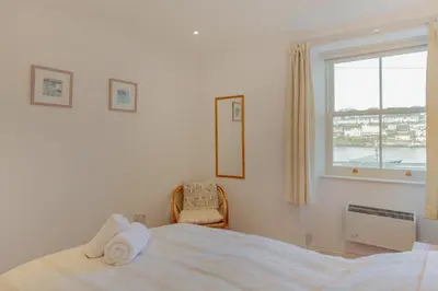 a white bedroom with a bed and a window at 2 Bed in Polruan oc-g30534 in Fowey