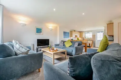 a living room with two blue couches and a table at 4 Bed in Newquay oc-c30589 in Saint Columb Major