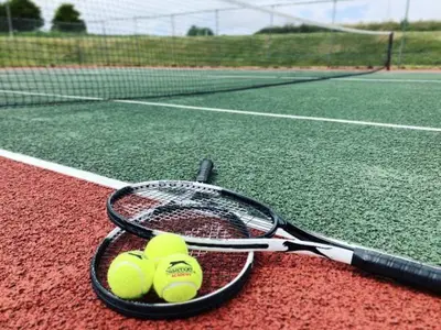 a tennis racket and three tennis balls on a tennis court at 4 Bed in Newquay oc-c30589 in Saint Columb Major