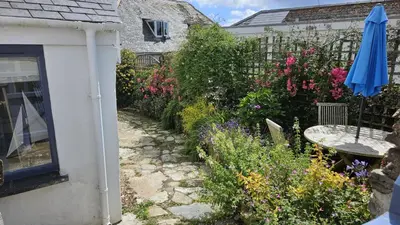 a garden with a blue umbrella and some flowers at Workshop in Saint Mawes