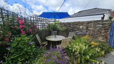 a table with chairs and an umbrella in a garden at Workshop in Saint Mawes