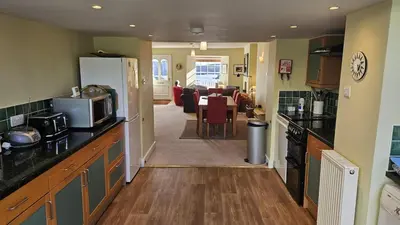 a kitchen with a counter and a living room at Charlies in Saint Mawes