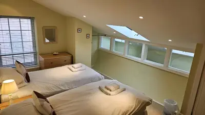 two beds in a room with two windows at Charlies in Saint Mawes