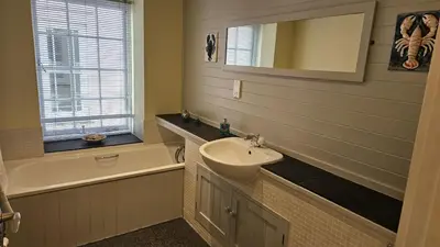 a bathroom with a sink and a bath tub at Charlies in Saint Mawes