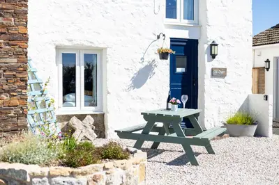a picnic table outside of a white house with a blue door at The Sty, rural retreat for couples in Falmouth