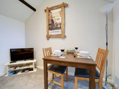 a dining room table with two chairs and a television at The Sty, rural retreat for couples in Falmouth