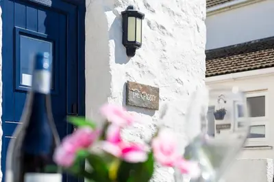 a building with a blue door and some pink flowers at The Sty, rural retreat for couples in Falmouth