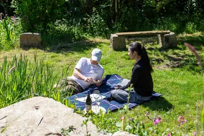 a man and woman sitting on a picnic blanket in the grass at The Sty, rural retreat for couples in Falmouth