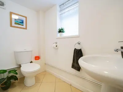 a white bathroom with a toilet and a sink at The Sty, rural retreat for couples in Falmouth