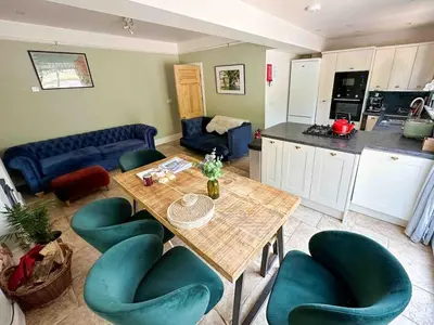 a living room with a table and chairs and a kitchen at Skylark House Padstow, Stylish Victorian Townhouse, Private Sauna, Cold Plunge and Log Burner in Padstow
