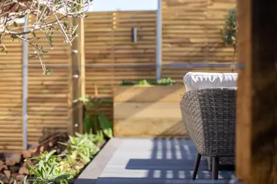 a patio with a chair and a wooden fence at Skylark House Padstow, Stylish Victorian Townhouse, Private Sauna, Cold Plunge and Log Burner in Padstow