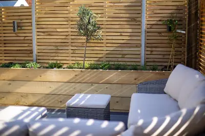 a patio with white furniture and a wooden fence at Skylark House Padstow, Stylish Victorian Townhouse, Private Sauna, Cold Plunge and Log Burner in Padstow