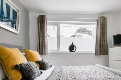 a bedroom with a bed with yellow pillows and a window at Life of Riley in St Ives
