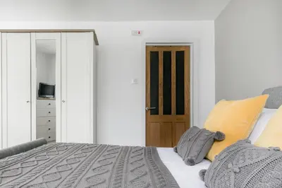a bedroom with a bed with yellow pillows and a door at Life of Riley in St Ives