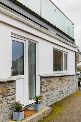 a white house with a window and two potted plants at Life of Riley in St Ives