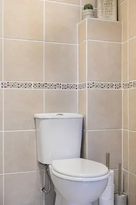 a bathroom with a toilet and a tiled wall at Life of Riley in St Ives