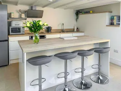 a kitchen with a counter with stools and a vase of flowers at Greycott - Uk48746 in Crantock