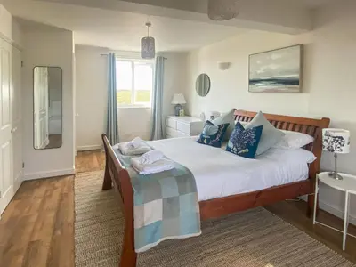 a bedroom with a bed with white sheets and blue pillows at Greycott - Uk48746 in Crantock